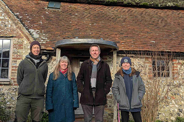 James outside the Clergy House, a very old brick building, in Alfriston. The sky is blue but all are dressed for cold weather.