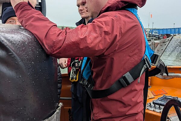 James in safety gear on a wet day talking to crew on a lifeboat