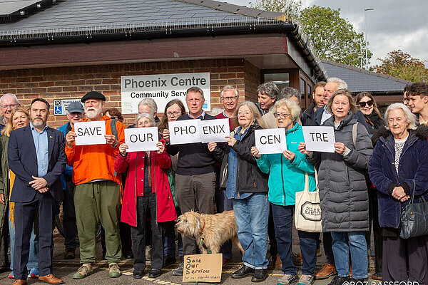 James MacCleary, with many people around him holding up signs that spell out Save Our Phoenix Centre.