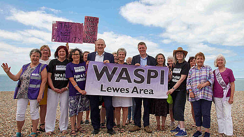 James and Ed with a group of women, all facing the camera, and holding a large sign that says "Waspi Lewes Area". Several of the women are wearing t-shirts with "Fair and fast solution"