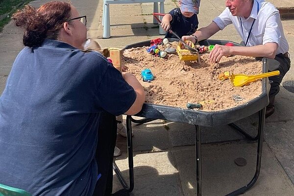 James with a nursery worker and a child playing with a raised sandpit (good practice for the House of Commons)