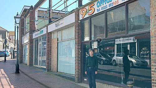 Councillor Carolyn Lambert standing in front of some rather down at heel shops with the remnants of what was the first floor of the building above them.