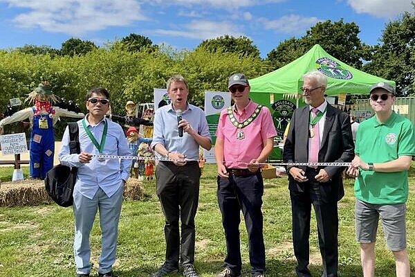 James, with microphone and scissors, among various dignitaries, officially opens the Polegate Fun Day. There is a scarecrow carefully placed in the background.