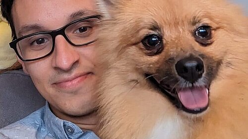 Penny, a medium sized long haired terrier type dog with a pointed nose, dark eyes and an energetic expression, with Councillor Freddie Hoareau