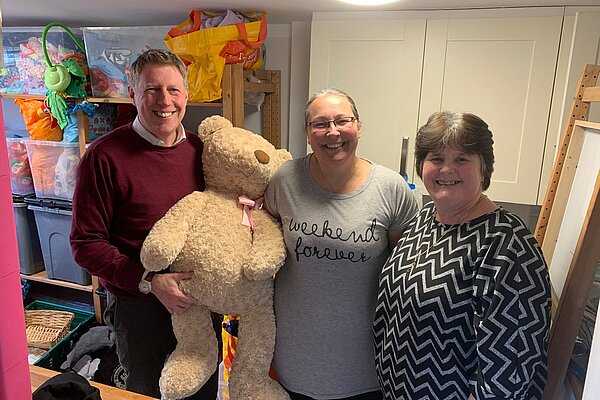 James with two staff of Seahaven Baby Bank. James is holding a large teddy bear, which looks as if it will be going home with him.